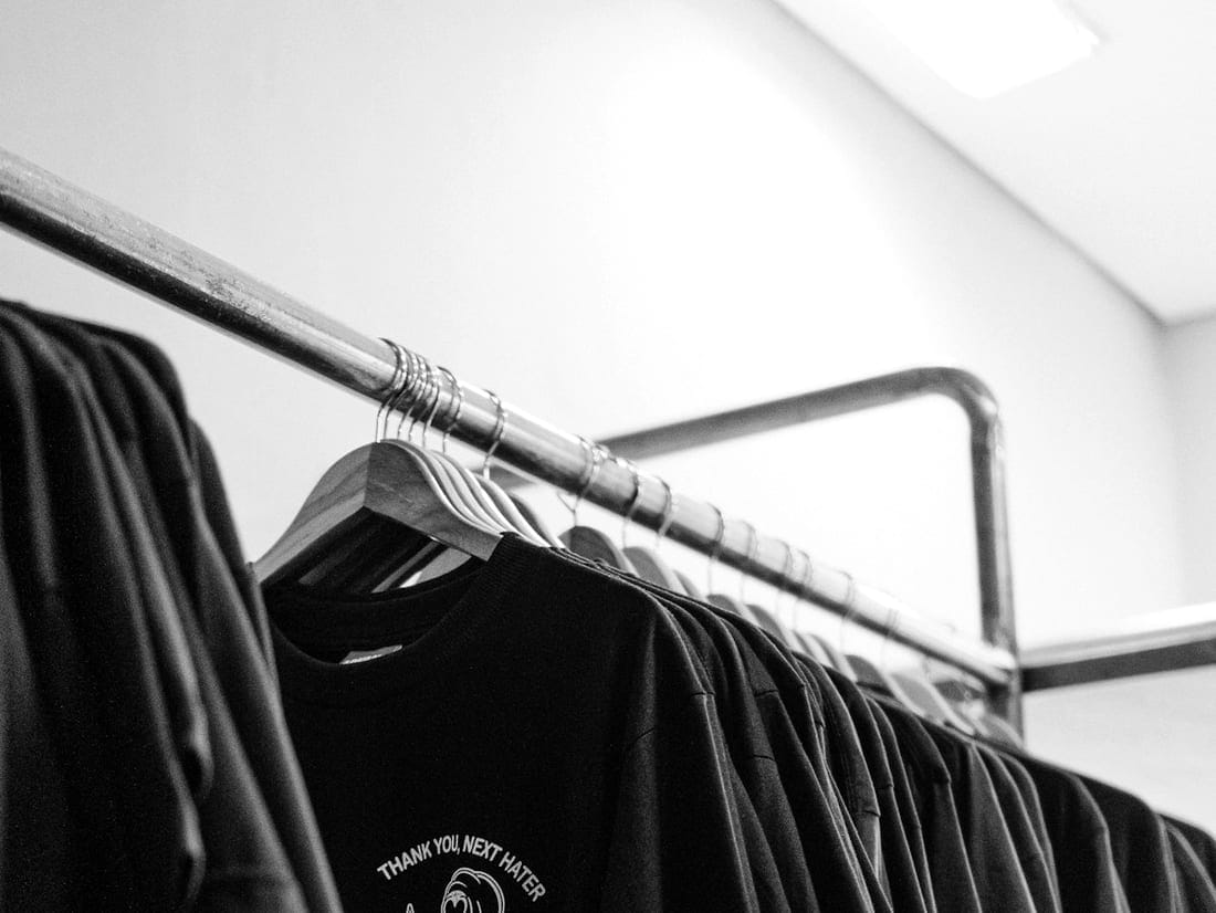 Knitwear — dark knits and tees resting on a rail
